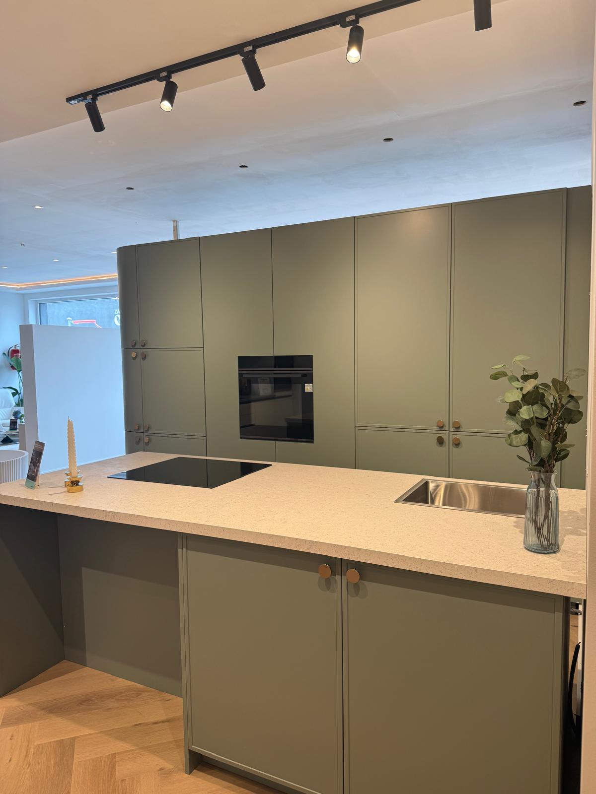 Landelijk-moderne keuken met groene kaderdeuren en licht werkblad
