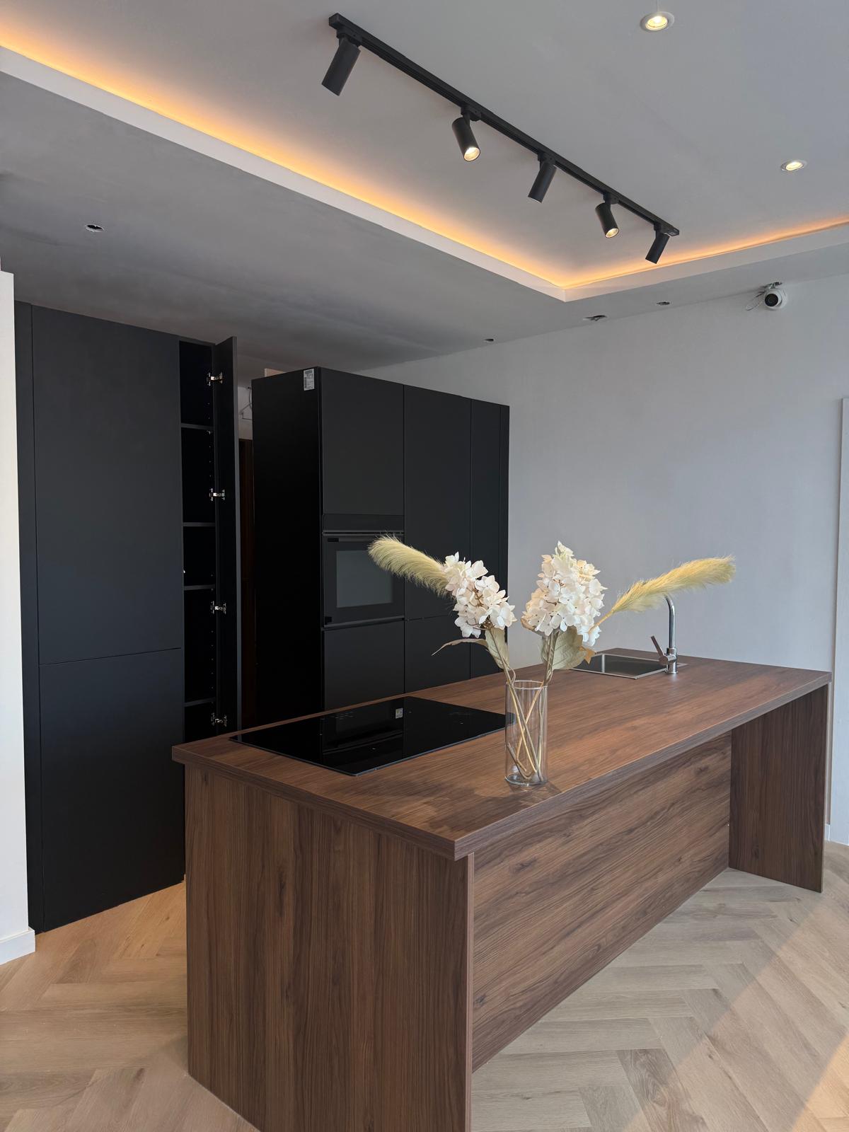 Moderne matzwarte keuken met walnoten eiland